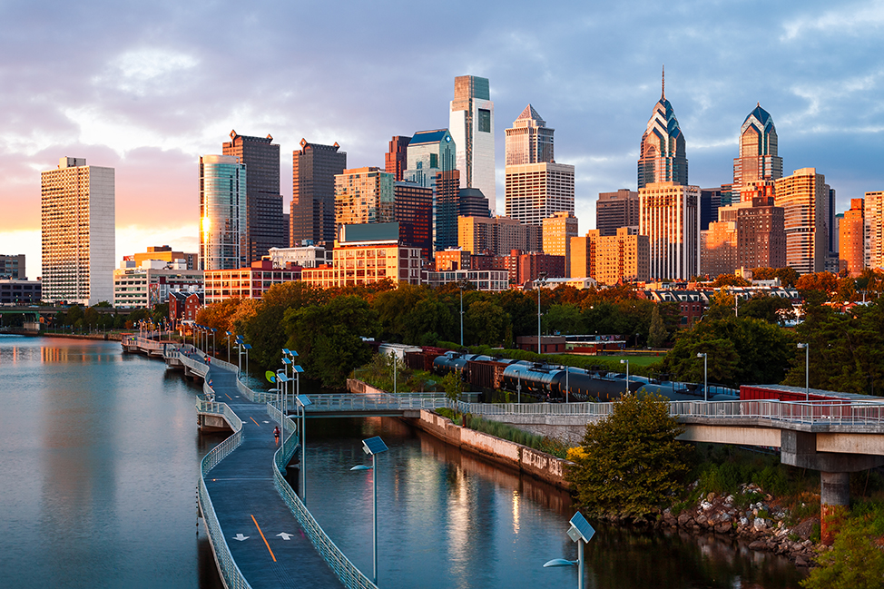 Sunset over the Philadelphia skyline and Schuylkill Banks Boardwalk, promoting YPrime’s appearance at OCT East Coast 2025. Visit booth #58 in King of Prussia, PA to explore clinical trial solutions.