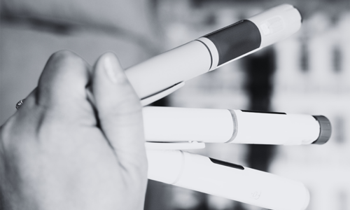 Close-up of a hand holding several small medical sample containers, symbolizing clinical research and data collection in GLP-1 weight management trials, with relevance to YPrime’s clinical trial technology and solutions.