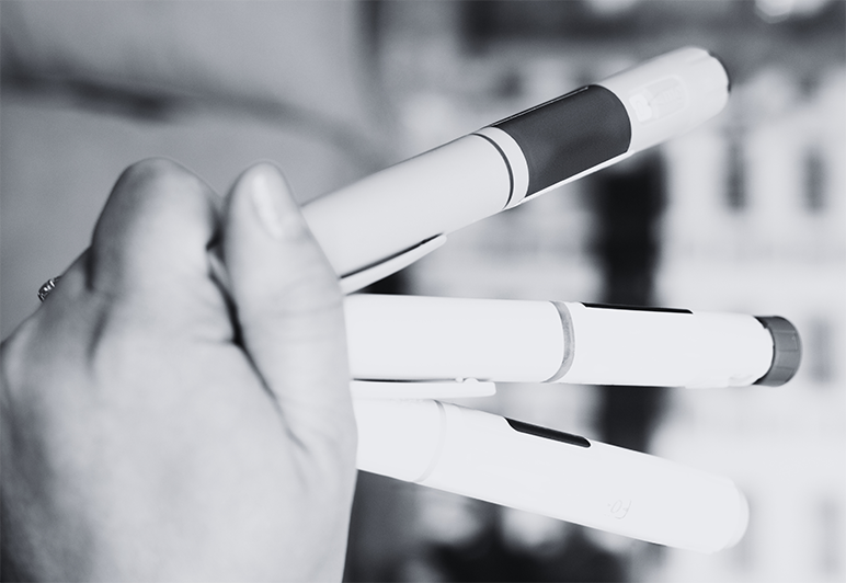 Close-up of a hand holding several small medical sample containers, symbolizing clinical research and data collection in GLP-1 weight management trials, with relevance to YPrime’s clinical trial technology and solutions.