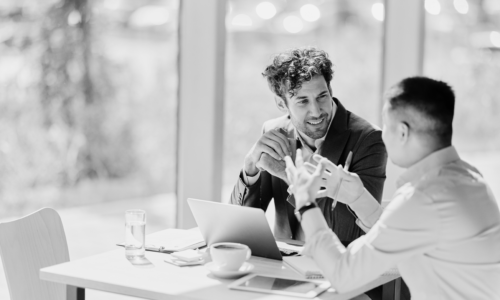 Two professionals discussing IRT compliance and E6(R3) guidelines over coffee with a laptop and tablet
