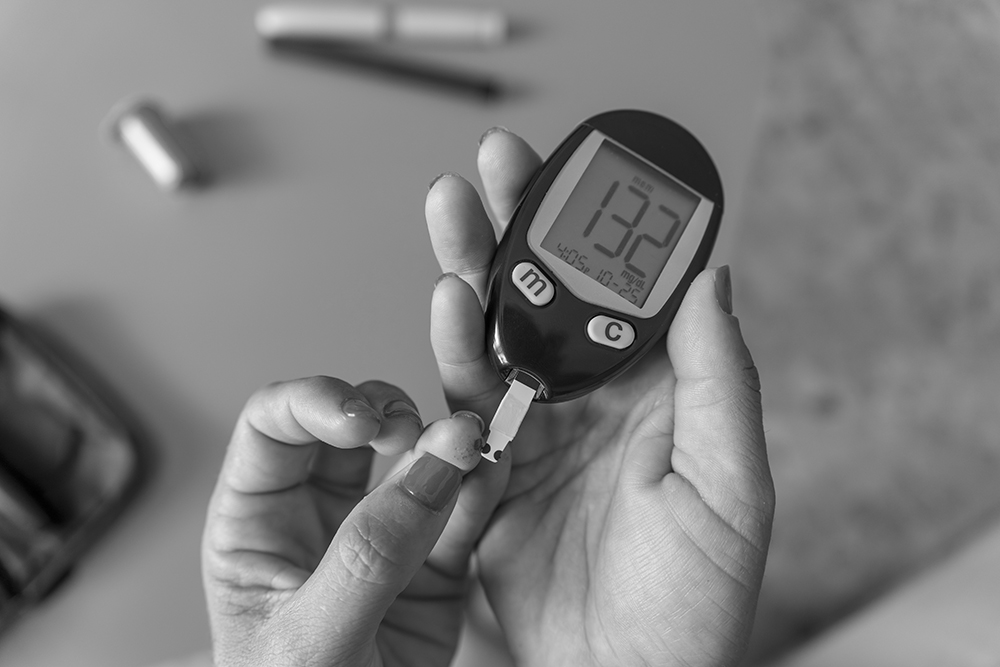 Woman using a glucometer for blood glucose monitoring in a clinical trial setting