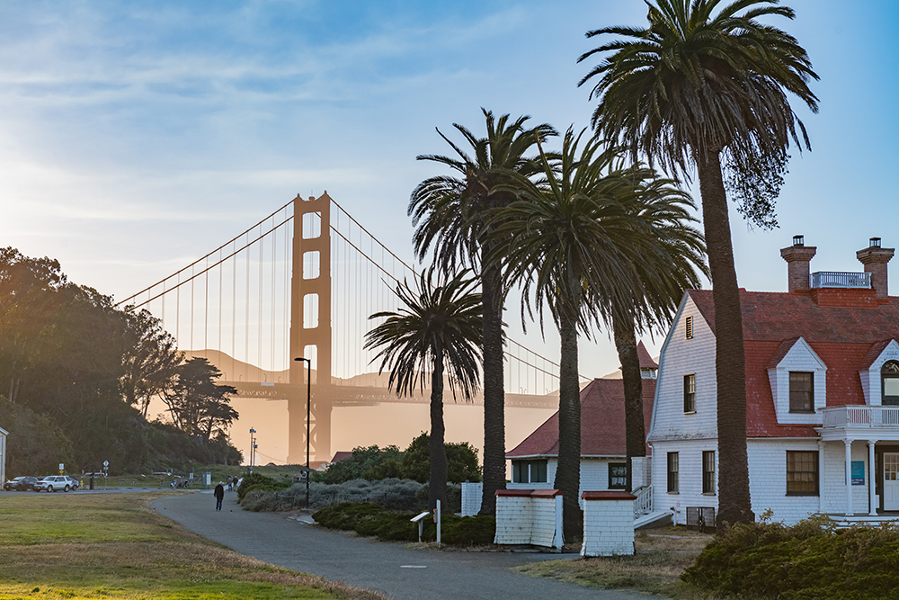 View of palm trees and San Francisco neighborhood with the Golden Gate Bridge in the background under a sunny blue sky, representing the CTS West Coast 2025 event location.