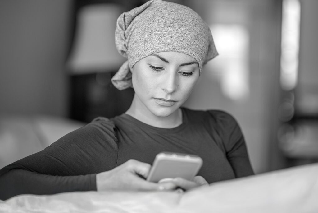 Woman wearing headscarf looking at smartphone, representing patient engagement in oncology clinical trials using eCOA tools
