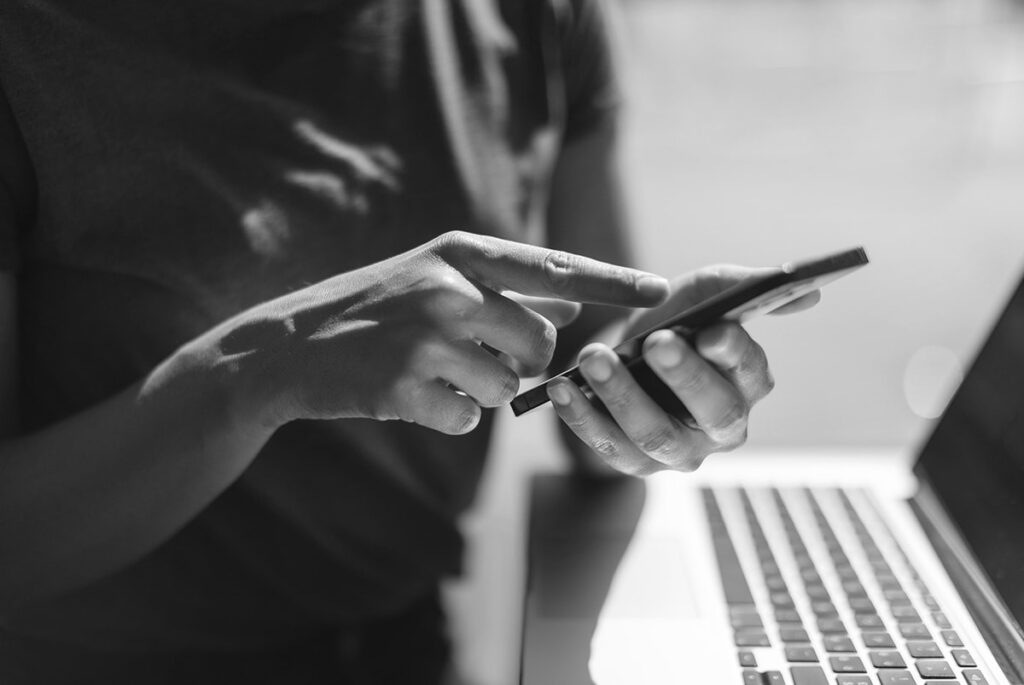Woman using smartphone and laptop, illustrating patient-centric eCOA strategies in rare disease clinical trials