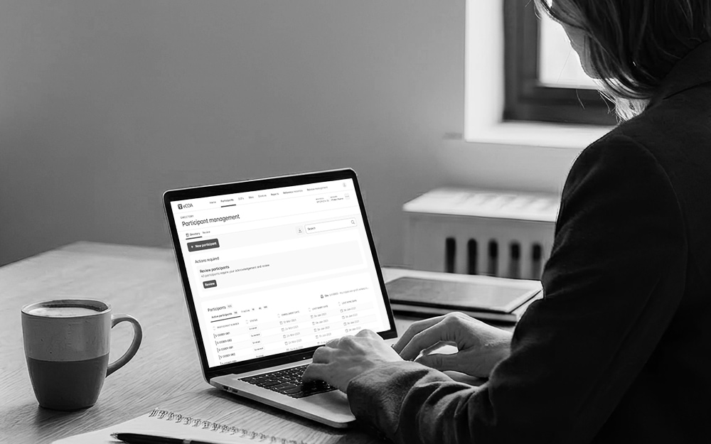 Clinical research professional reviewing eCOA participant management data on laptop for proactive trial oversight